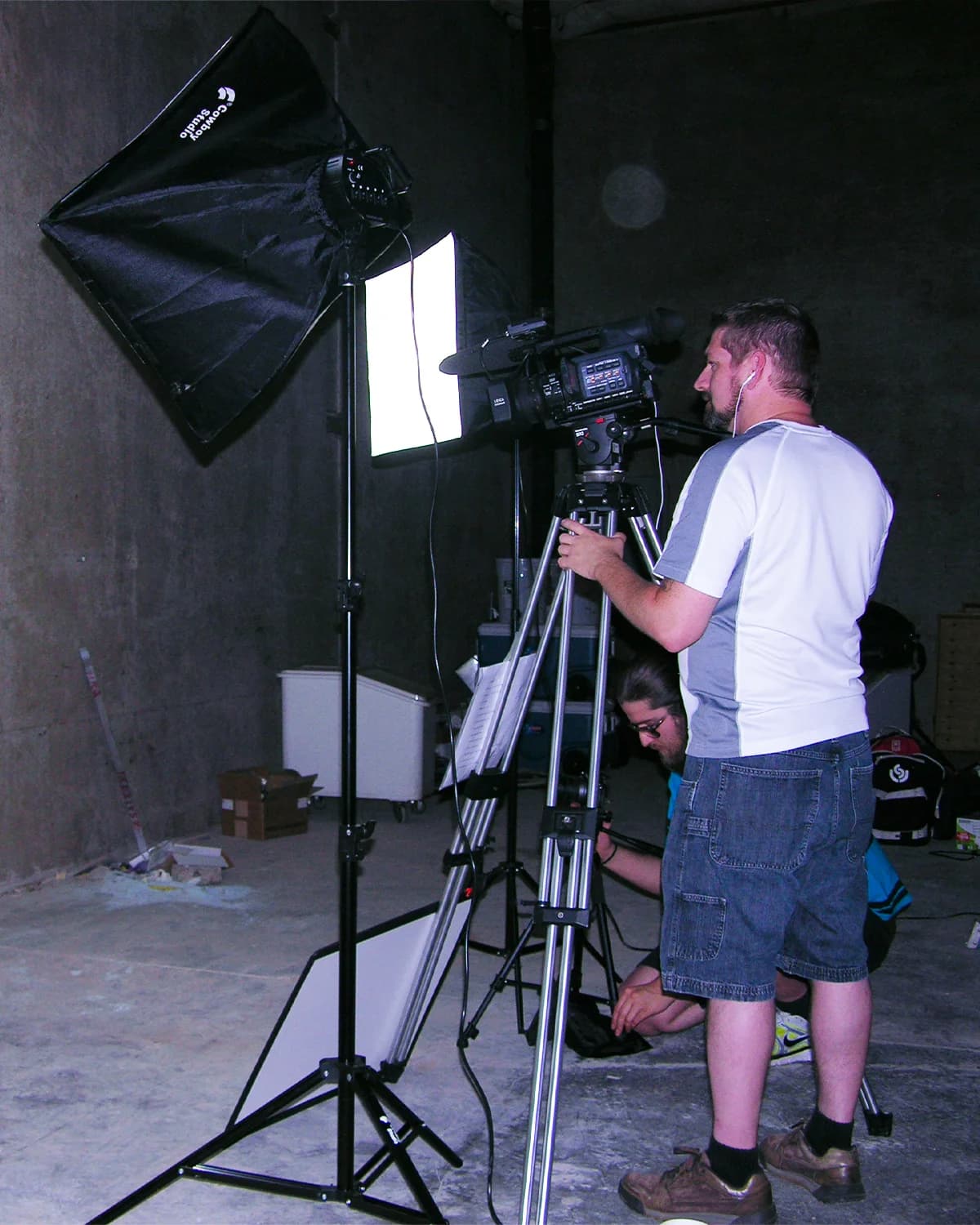 Filmmaker operating a professional video camera and lighting equipment during a film production