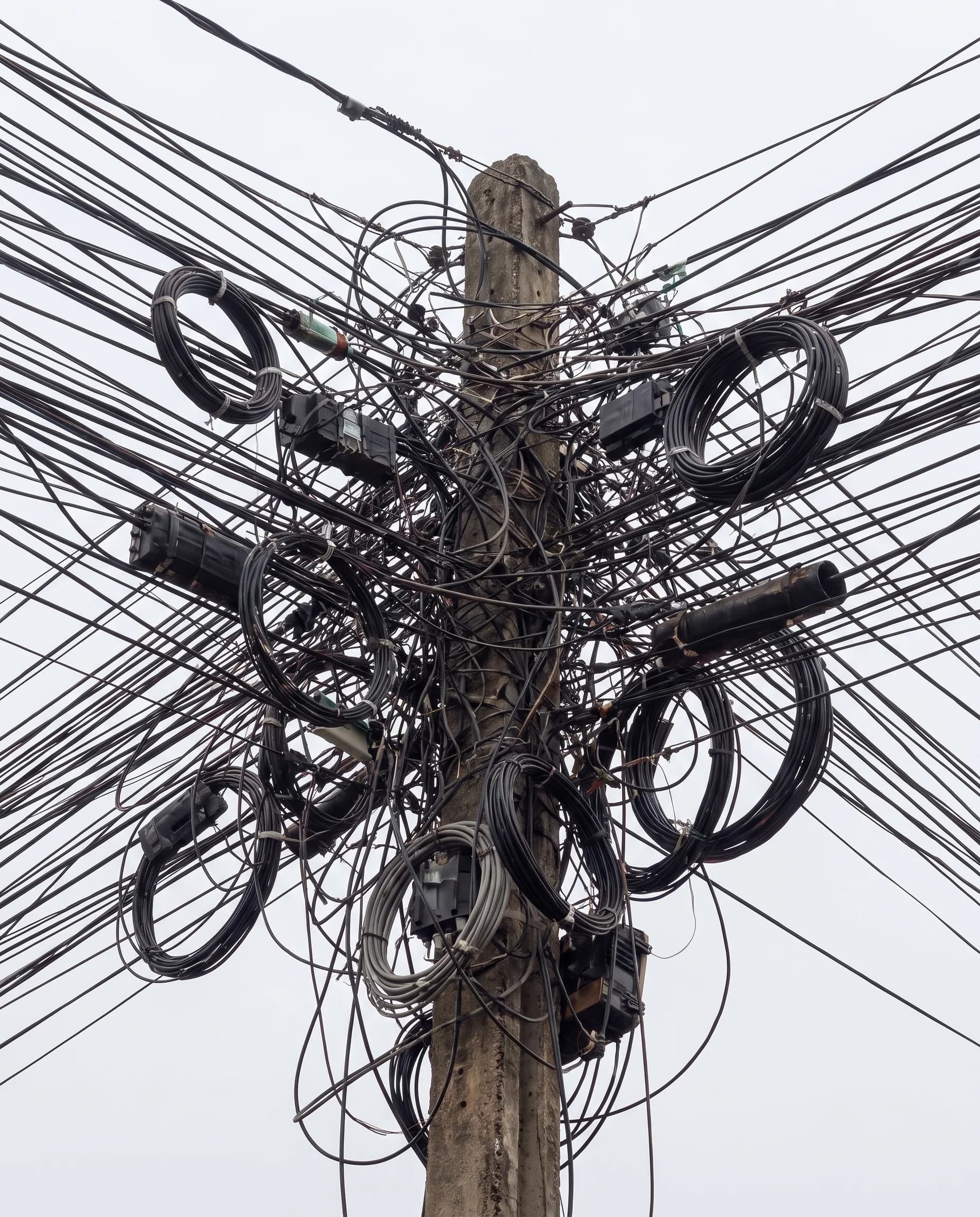 Complex network of cables and wires on a utility pole, representing the noise and information overload surrounding modern authors and storytelling